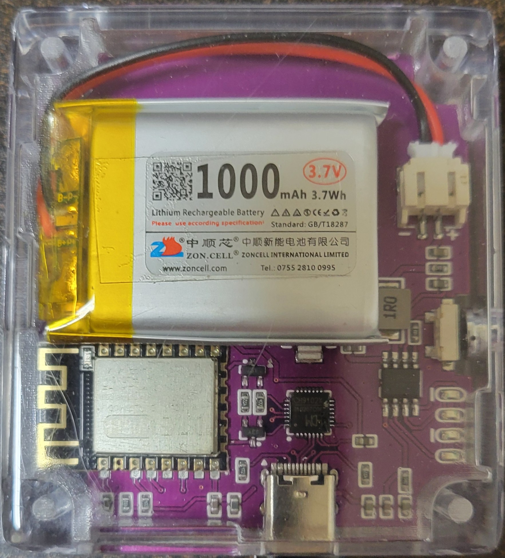 Back view of Jeff's Hackheld V1 — DSTIKE WiFi+ ESP8266 module top-left, ZON.CELL 1000 mAh LiPo occupying the upper third, USB-C connector on the bottom edge of the back PCB, CH340-class USB-to-seri…